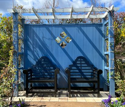 Compacte pergola in een kleine tuin met eettafel, sfeerverlichting en klimplanten voor lange zomeravonden