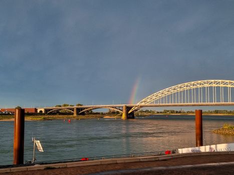 Weer vandaag Nijmegen boven de Waalbrug met donkere wolken, opklaringen en fietsers onderweg