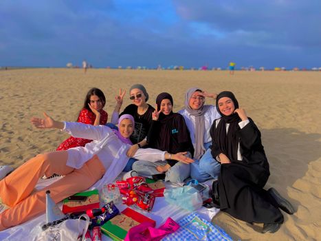 Vrouw leest het LINDA. Vakantieboek 2026 op een strandstoel met zonnebril, koffiebeker en zomerse vakantiesfeer